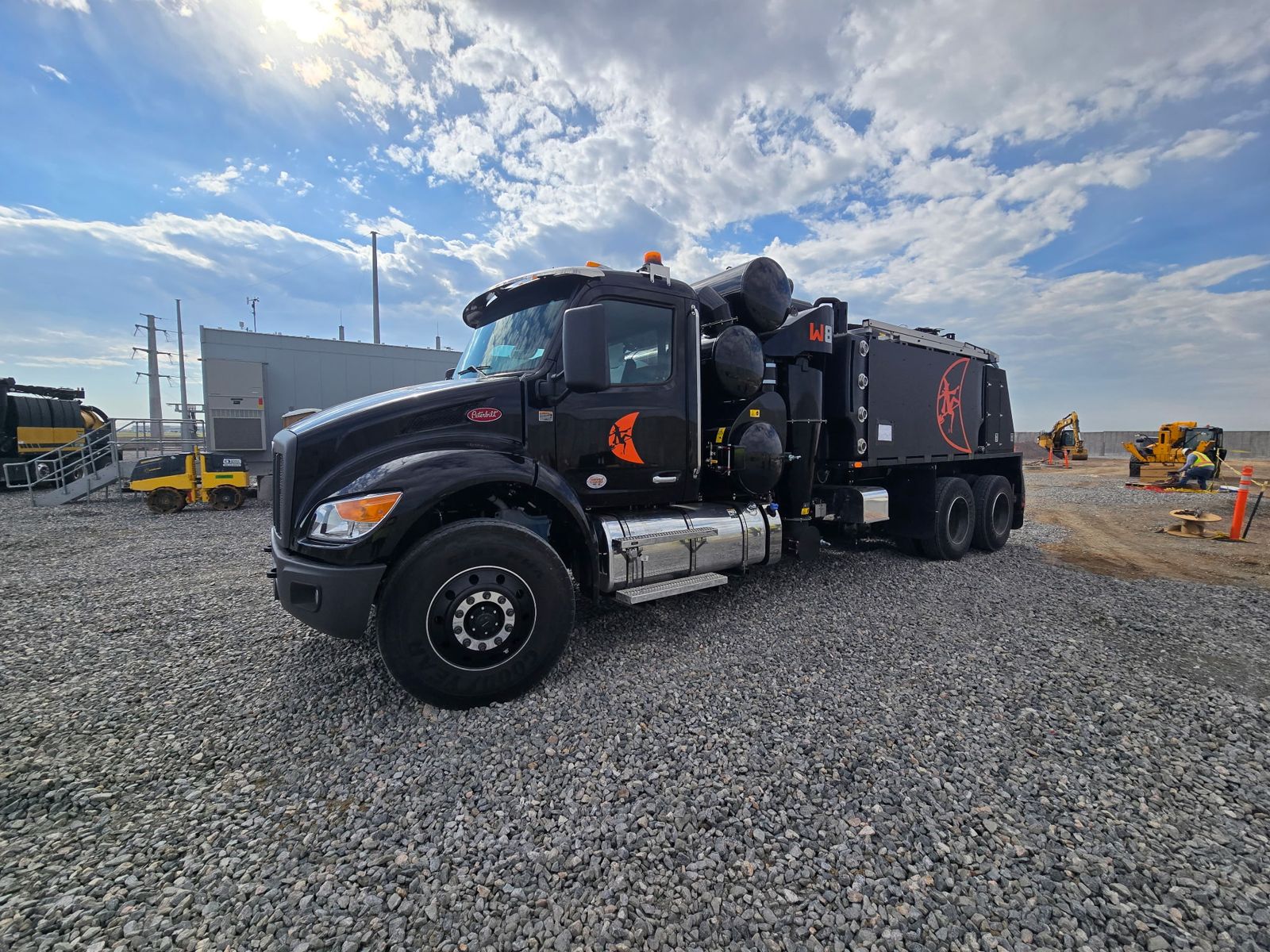 Black Peterbilt vacuum excavation truck at an industrial substation site
